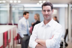 Smiling Businessman posing while colleagues talking together in background
